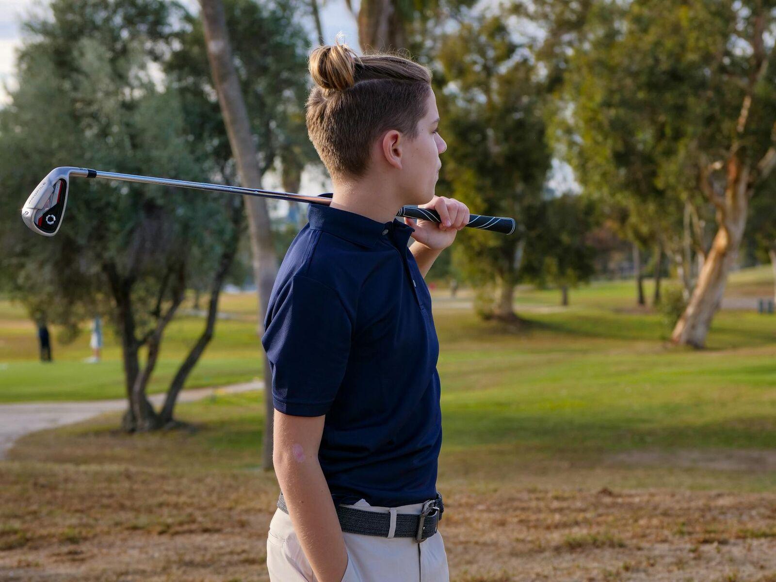 Junior golfer with an iron over his shoulder at golden hour